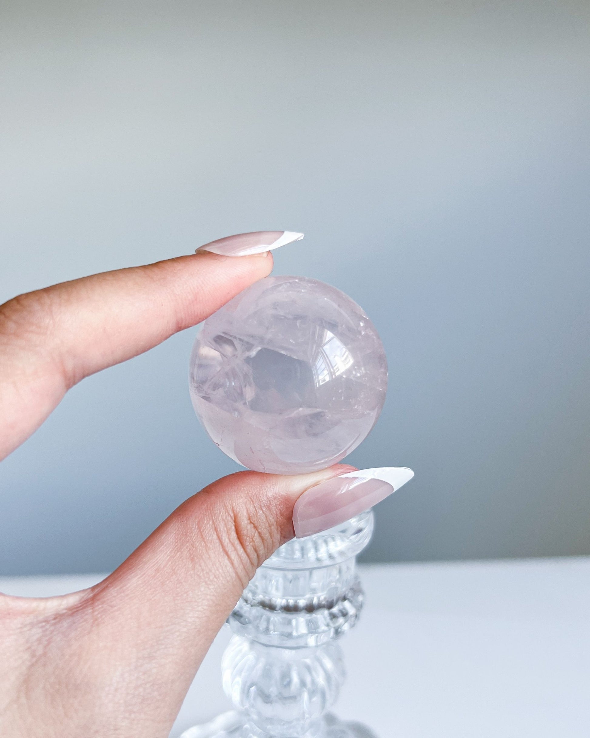 Side angle of Girasol Rose Quartz Sphere I with natural daylight, showing misty translucence and smooth surface