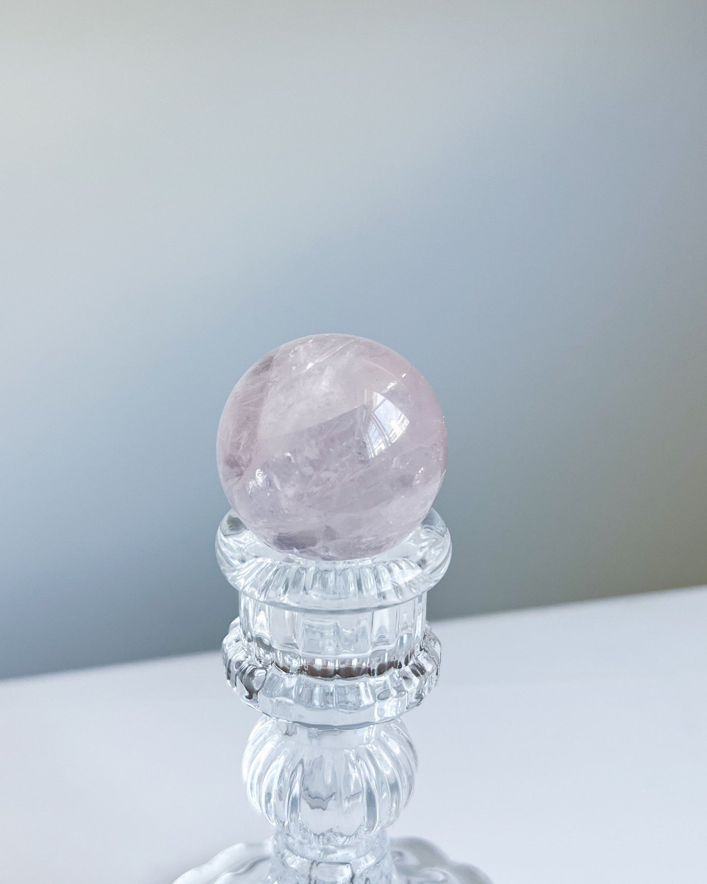 Girasol Rose Quartz Sphere I centered on a tall crystal stand, with a prominent horizontal band and radiant clarity