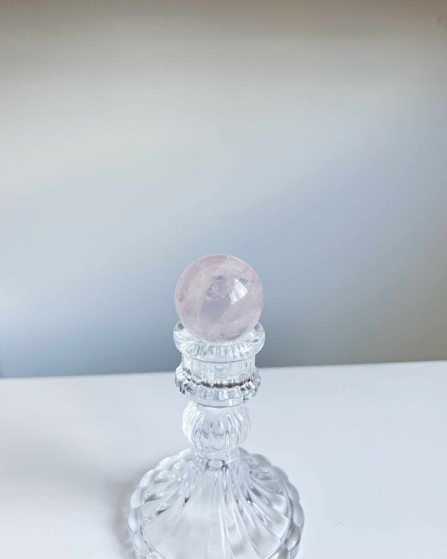 Girasol Rose Quartz Sphere I styled against a pale gradient backdrop, exuding ethereal elegance on pedestal