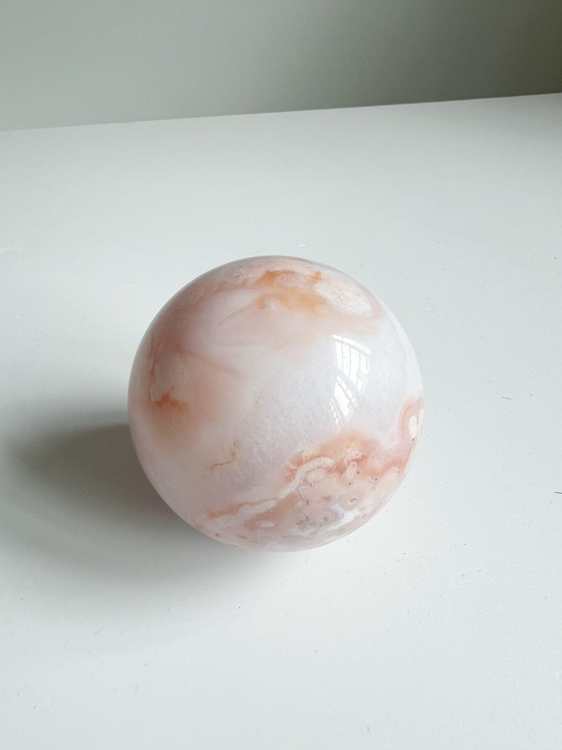 Carnelian Flower Agate sphere in soft cream and peach tones, with delicate swirling patterns