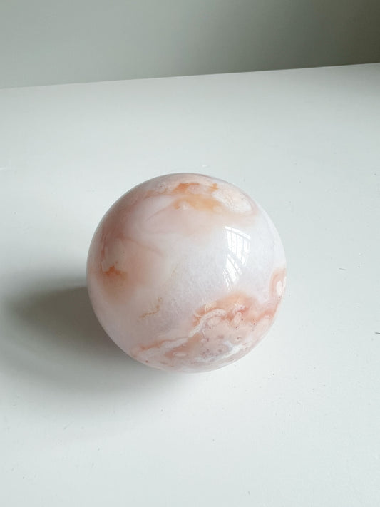 Carnelian Flower Agate sphere in soft cream and peach tones, with delicate swirling patterns