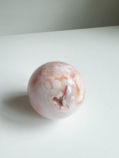 Crystal sphere with a natural geode opening, framed by blush and coral floral inclusions