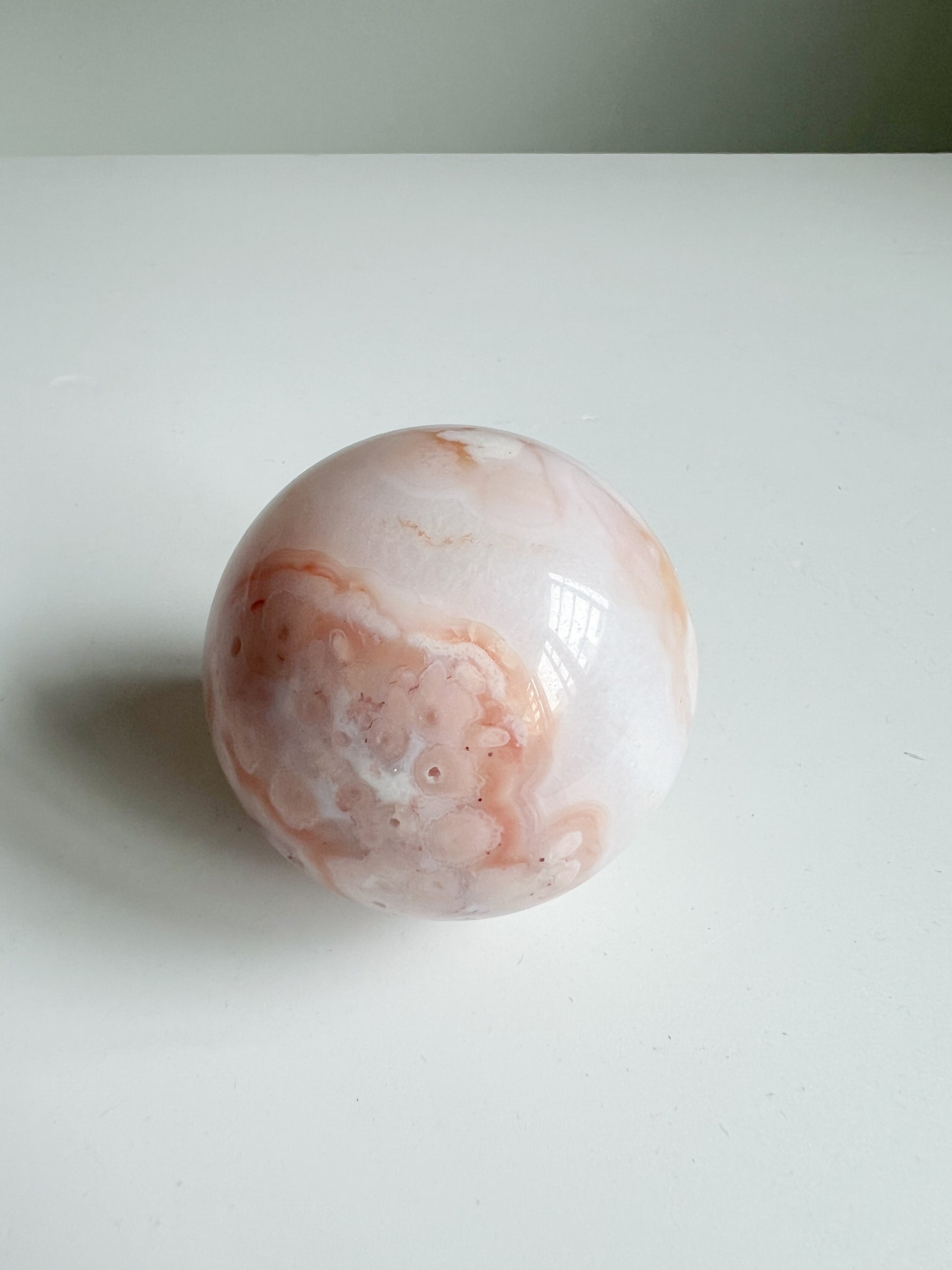 Top-down view of a soft-toned Carnelian Flower Agate sphere with blush bloom patterns