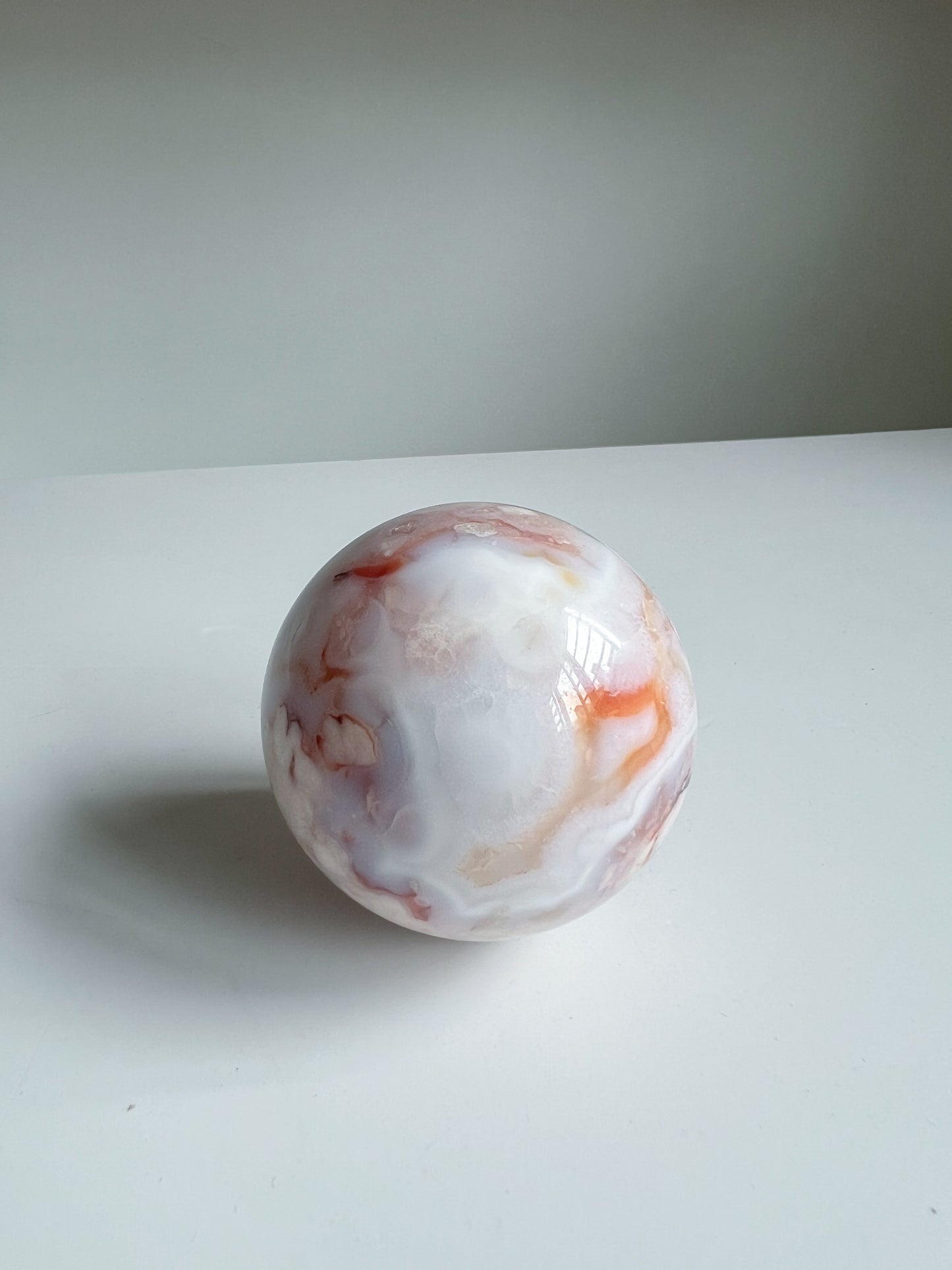 Creamy blue pastel carnelian flower agate crystal sphere with orange swirls, named Aurora
