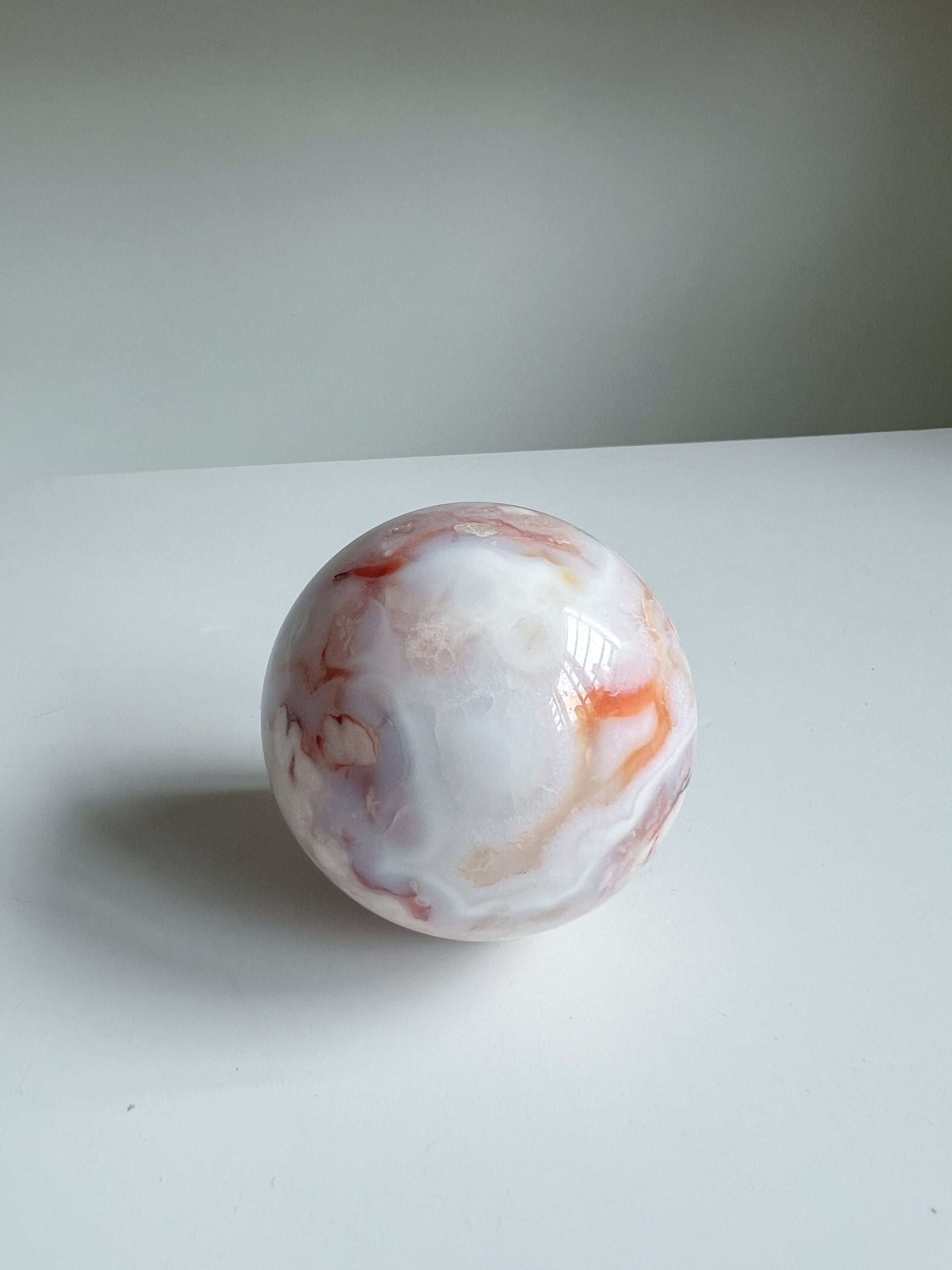 Creamy blue pastel carnelian flower agate crystal sphere with orange swirls, named Aurora