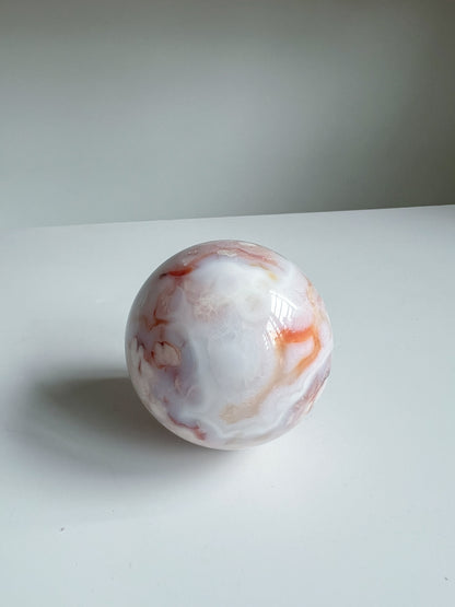 Creamy blue pastel carnelian flower agate crystal sphere with orange swirls, named Aurora