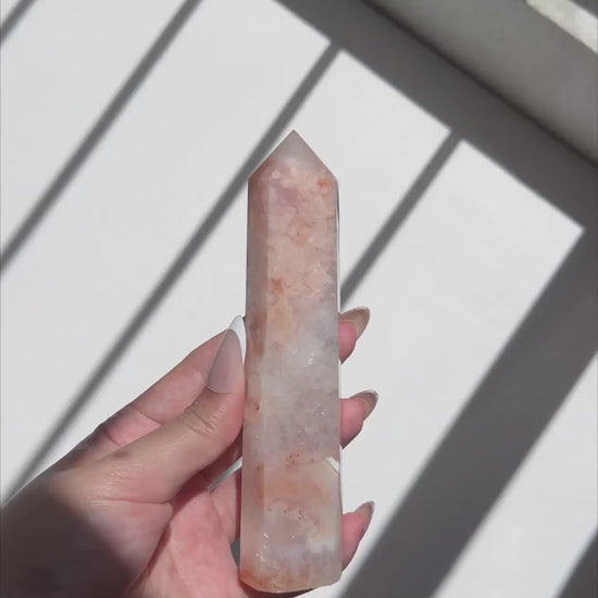 Video of hand holding a Carnelian Flower Agate tower with blush pink and translucent white patterns