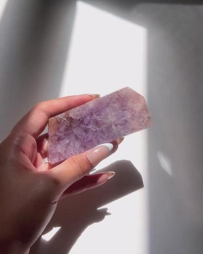 Hand holding polished purple flower agate slab under sunlight and natural daylight