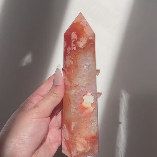 Video of hand holding a Carnelian Flower Agate tower, showing dense white crystal core with surrounding petal-like inclusions