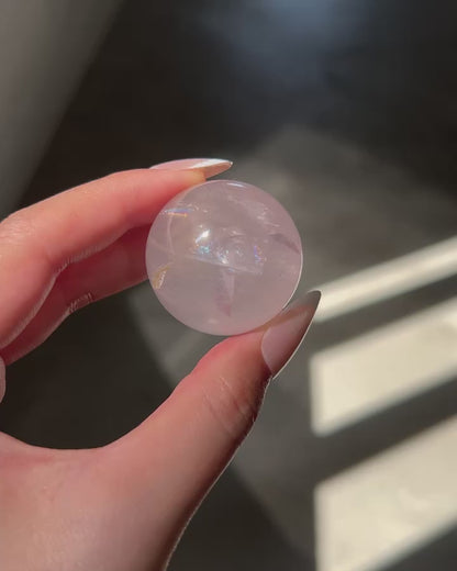Close-up of a Girasol Rose Quartz sphere held in hand in three different lightings: sunlight, with flash and studio lighting: revealing rainbows, clarity, asterism and golden healer.