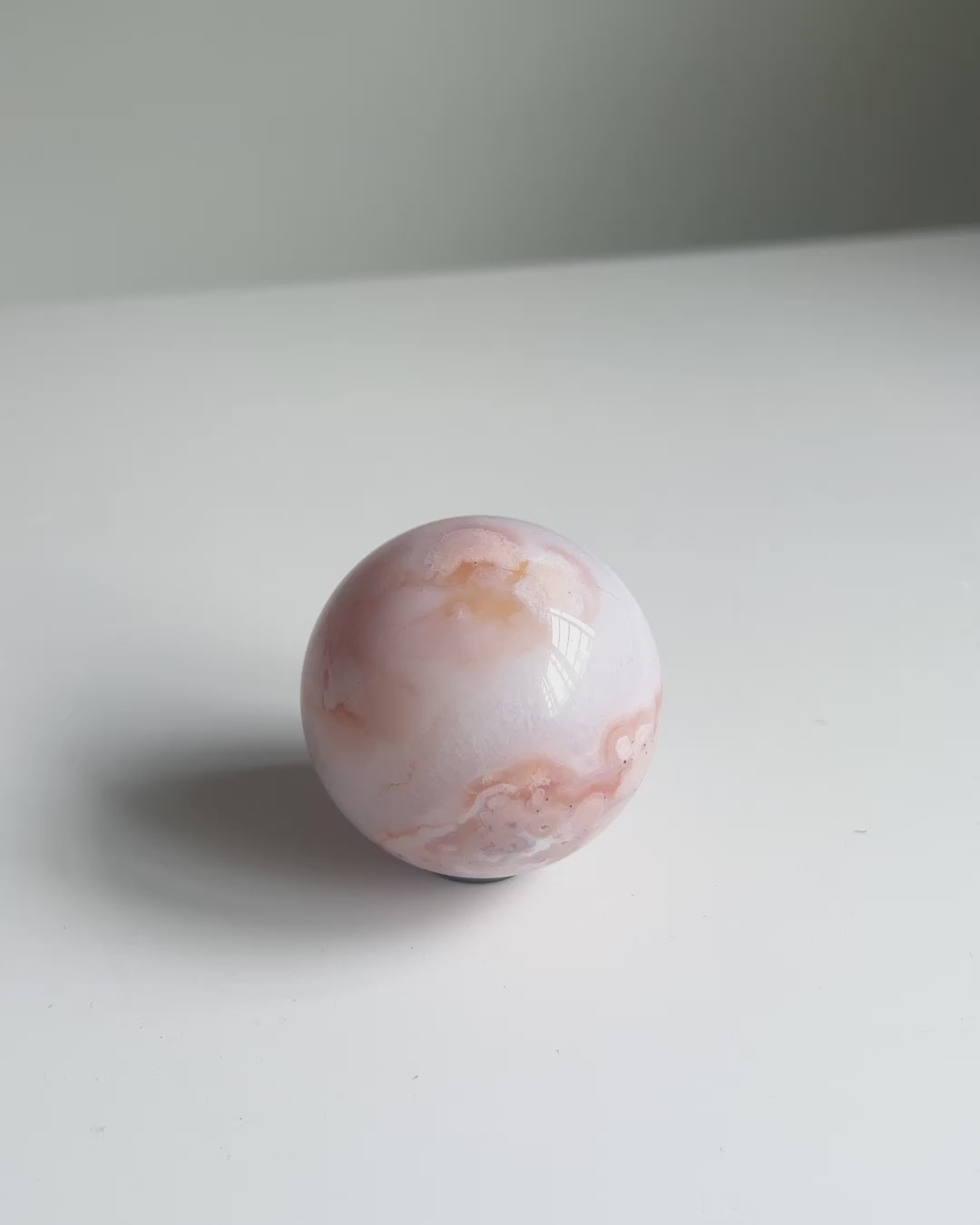 Video of a soft-toned pastel Carnelian Flower Agate sphere in natural daylight and sunlight
